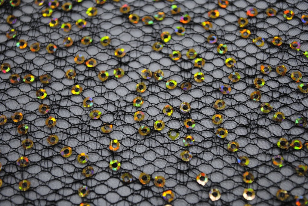Gold sequins on black spider mesh fabric - Fabric Universe